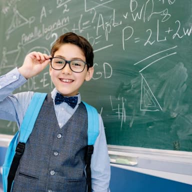 Young student with glasses in front of chalkboard